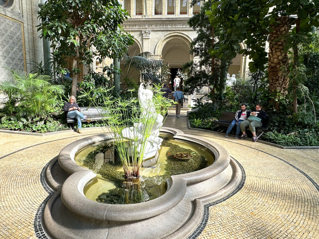 Personer som sitter vid fontän på museet Glyptoteket i Köpenhamn.