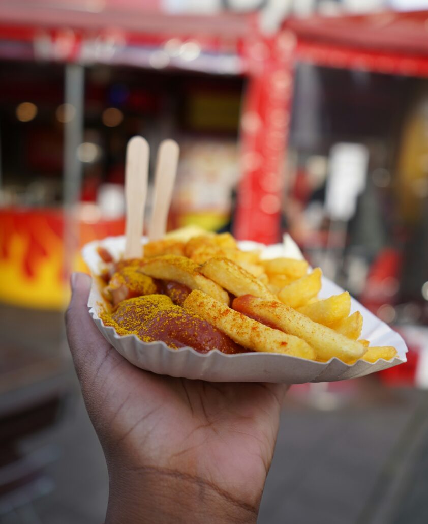 Person som håller upp en tallrik Currywurst