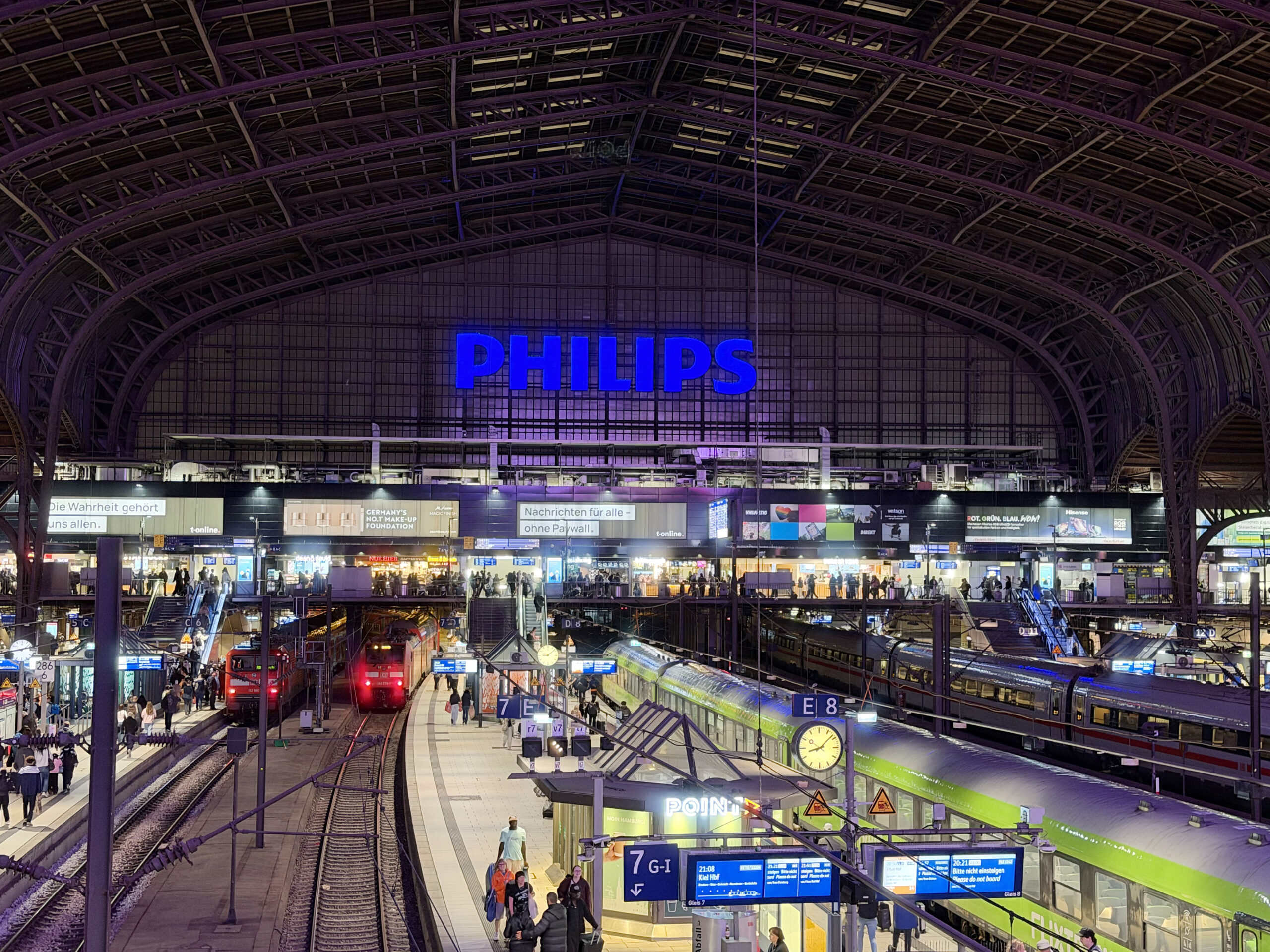 Resenärer och tåg på centralstationen i Hamburg under kvällstid.
