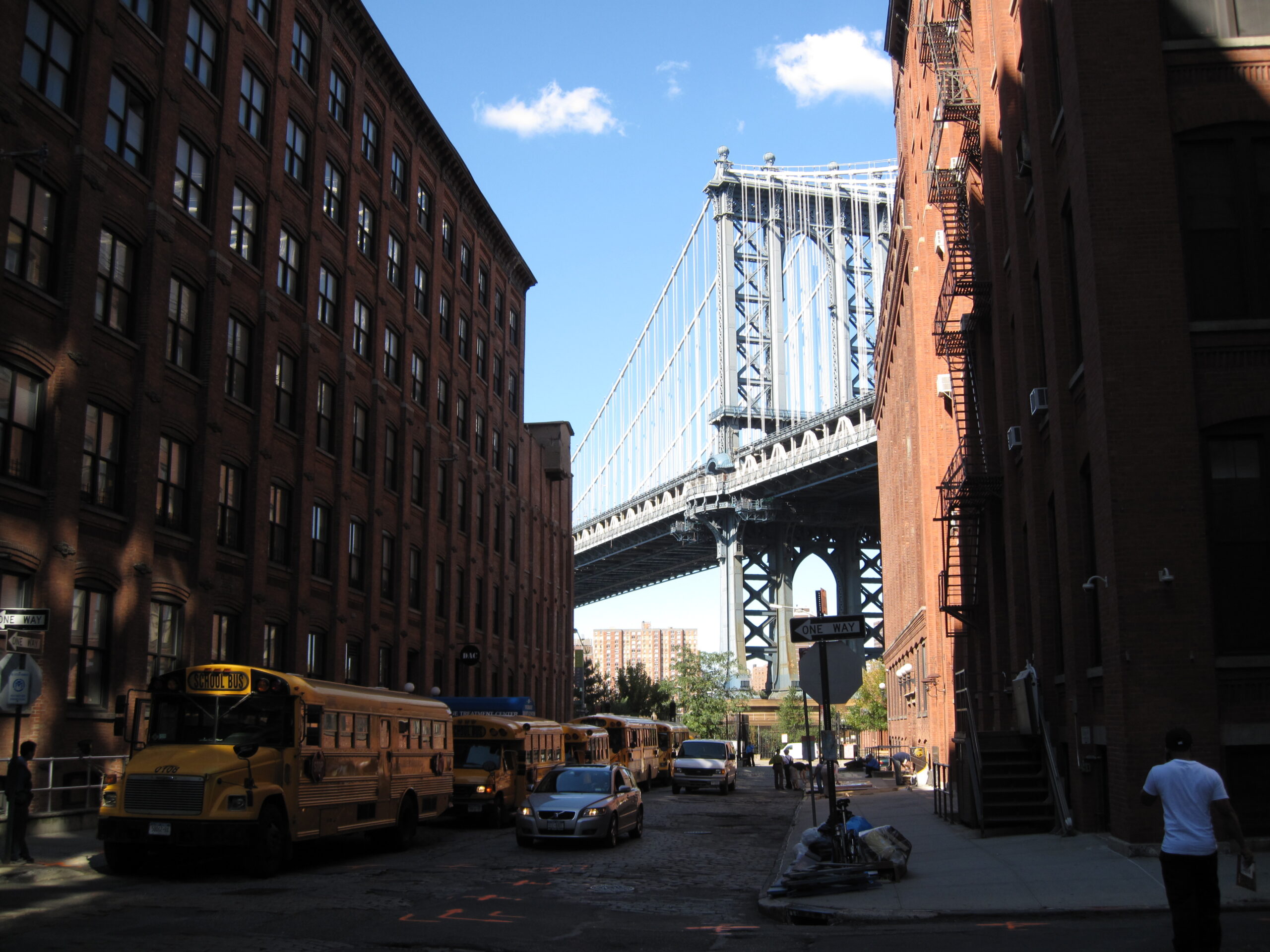 Skolbuss och trafik på gata vid byggnader vid Brooklyn Bridge i New York.