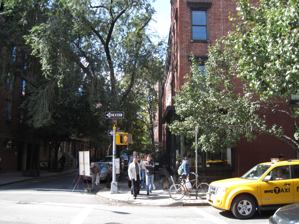 Människor vid övergångsställe, gul taxibil väntar på grönt ljus, en solig dag i New York.