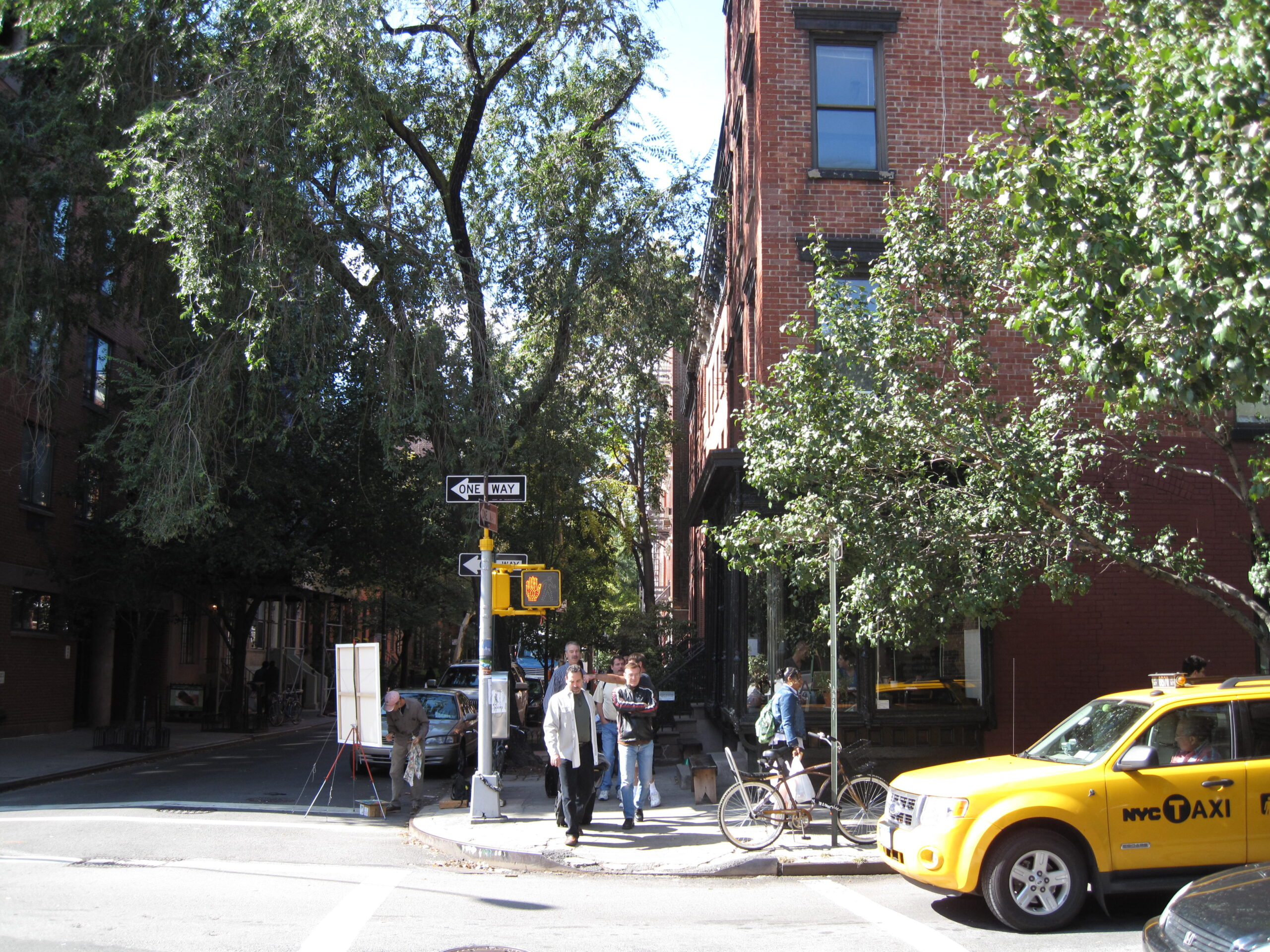 Människor vid övergångsställe, gul taxibil väntar på grönt ljus, en solig dag i New York.